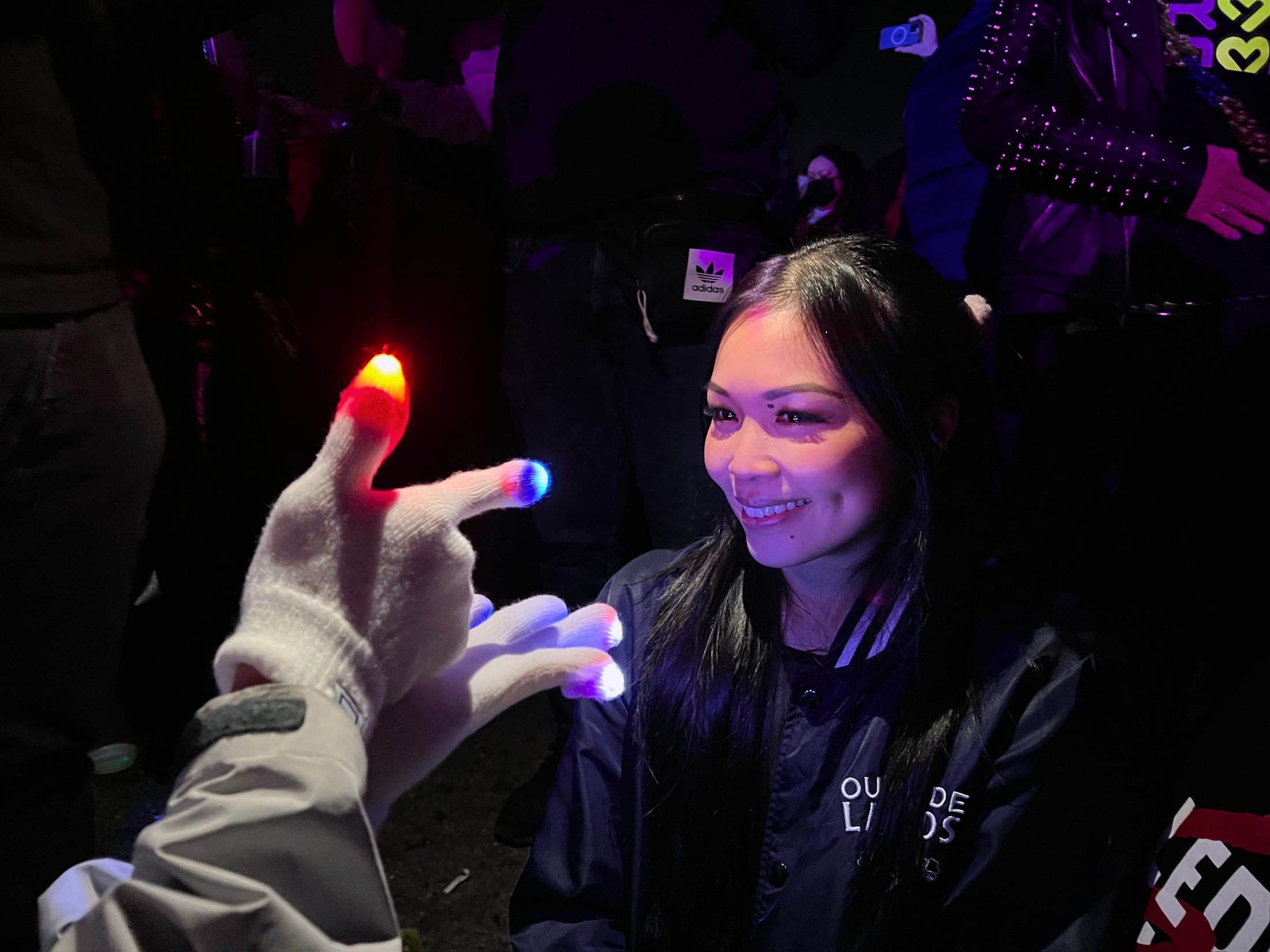 Glover reaching toward a smiling crowd member with lit gloves